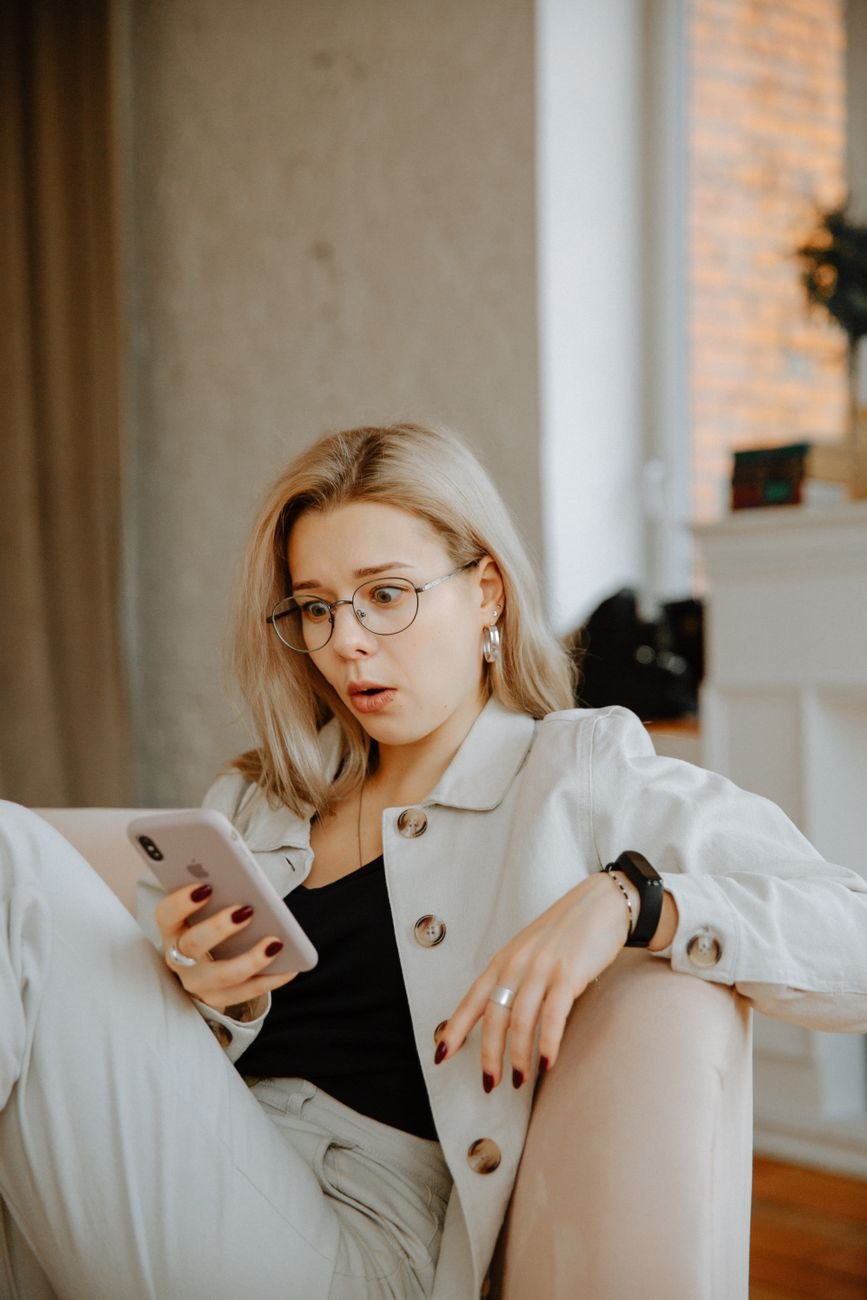 Woman smiling with surprise at good news on her phone